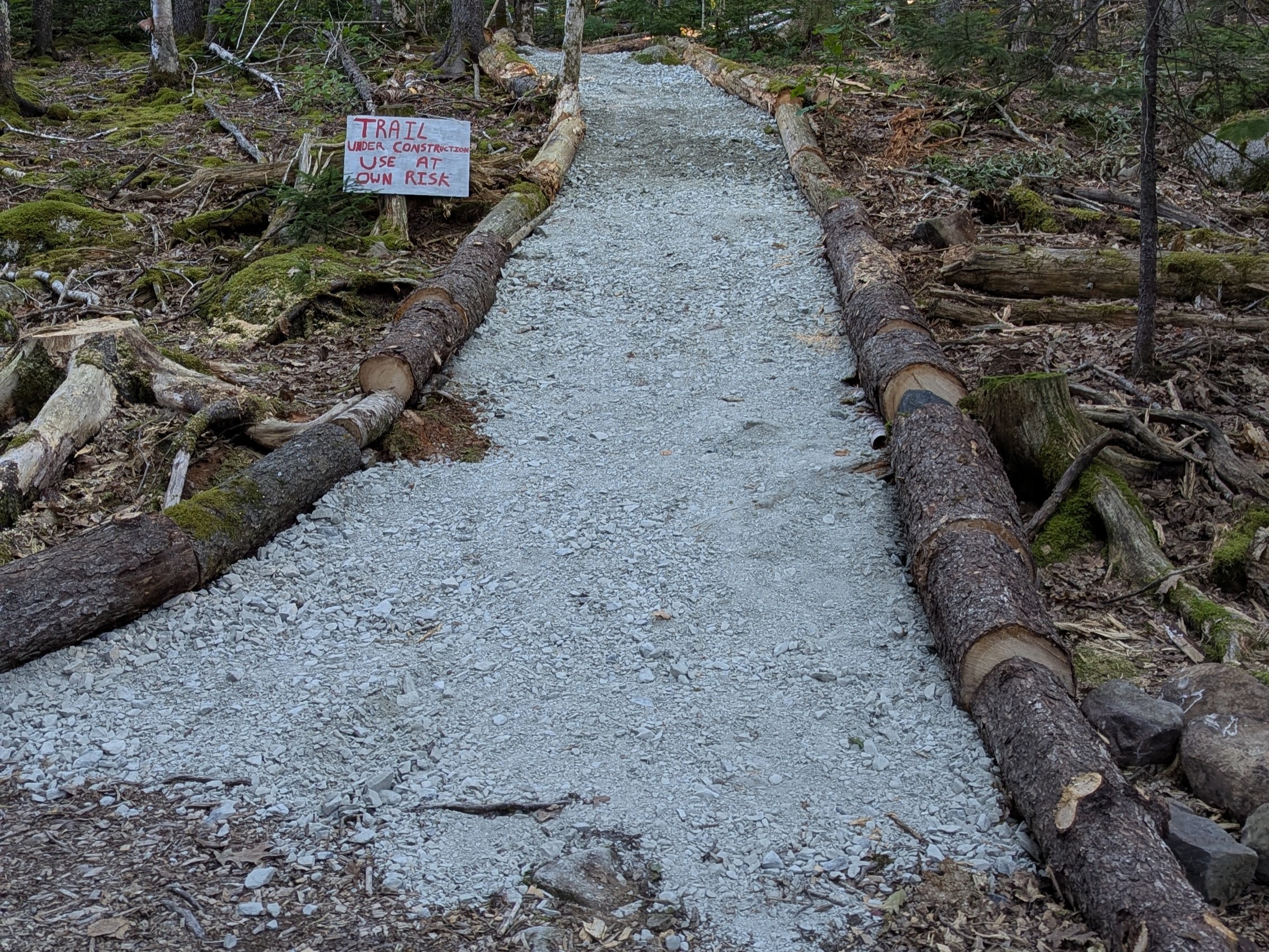 Slope trail gravel and log edging being installed